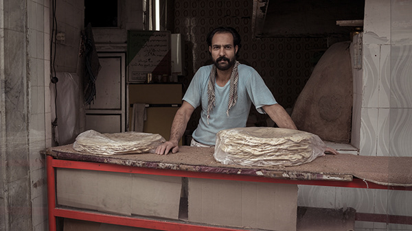 Vendor behind a stall displaying stacks of flatbread