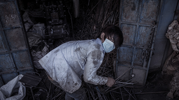Worker wearing a face mask inside a dim workshop