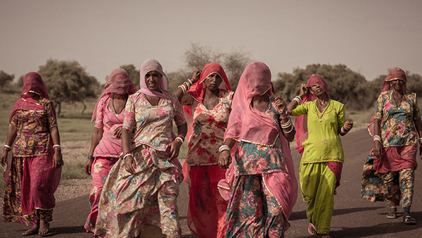 Women in colorful clothing walking across open land