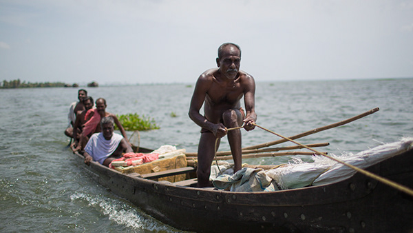 Man standing in a wooden boat on calm water