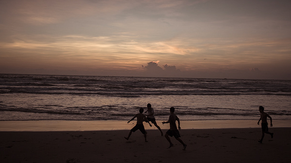 Silhouettes running along a beach at sunset