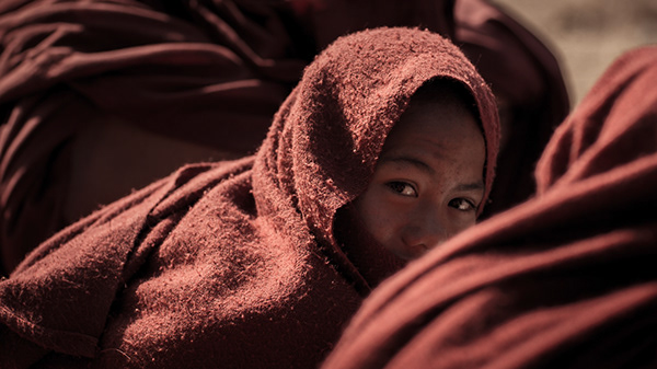 Child peeking out from a red patterned blanket