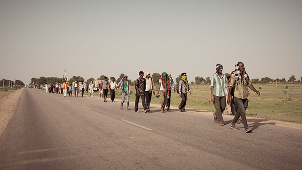 Group of people walking along a road in bright sunlight