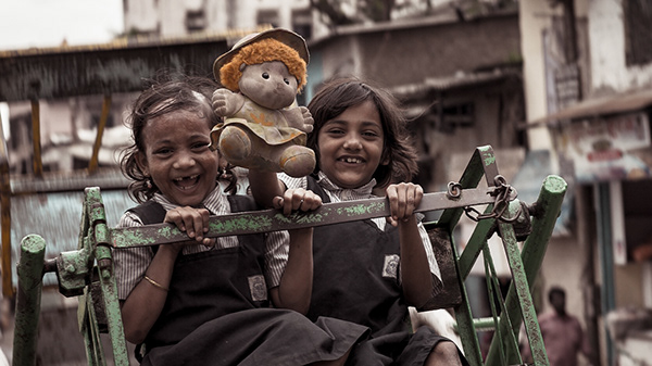Two smiling girls beside a decorated cart