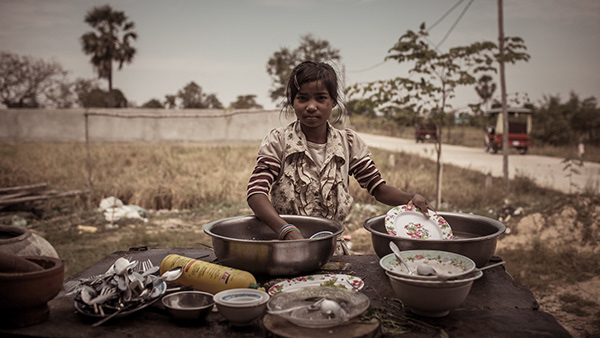 Man preparing food with several bowls beside a field