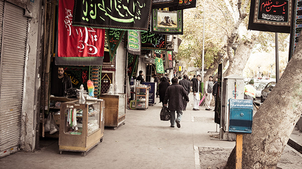 Pedestrians walking along a shaded shopping street