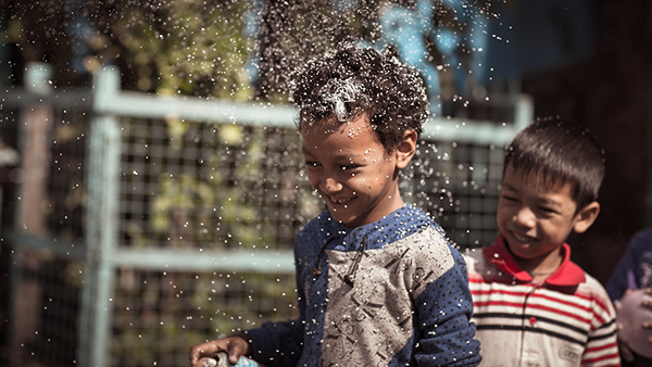 Children smiling as water splashes over one child's head