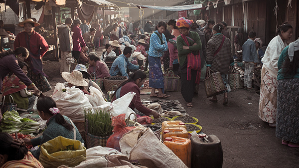 Shoppers walking between produce stalls on a narrow street
