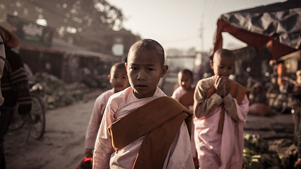 Young monk walking along a market street