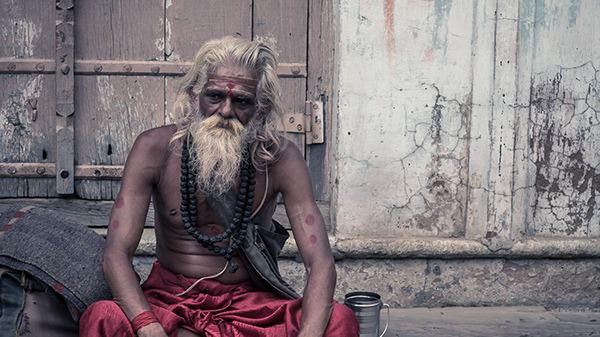 Bearded man sitting against a weathered wall