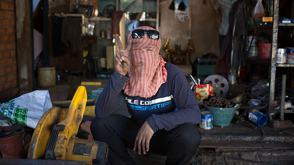Vendor sitting behind produce at a market stall