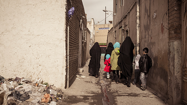 People walking down an alley beside tall walls