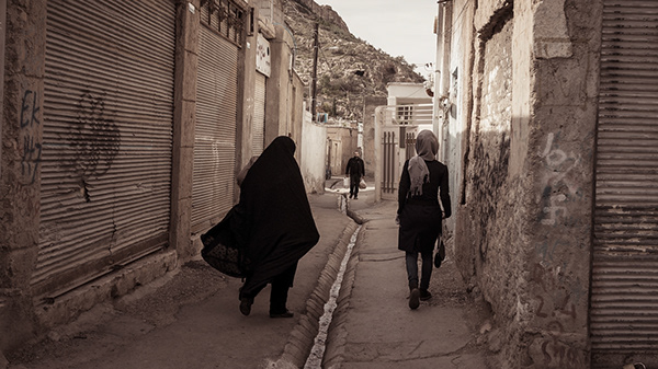 People walking through a narrow brick-lined alley
