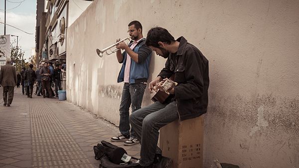 Men gathered beside a wall on a narrow street