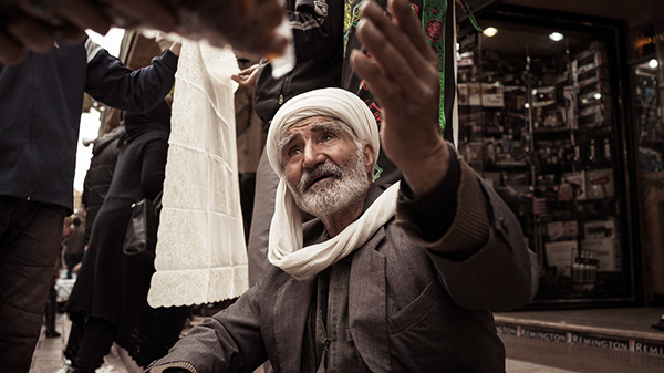 Older man raising a hand on a street